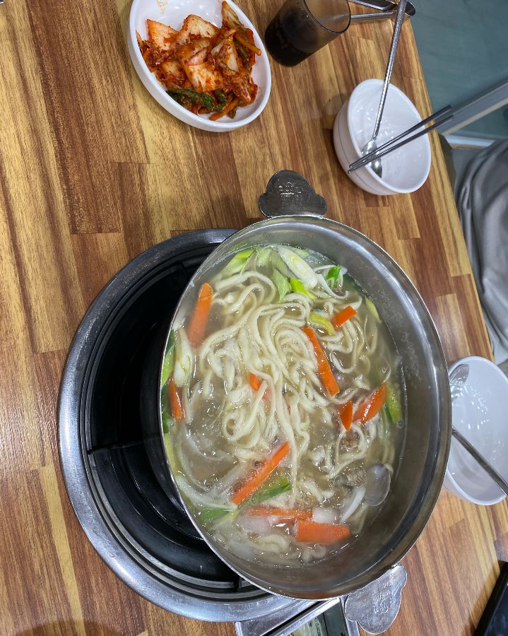 테이블 위에 놓인 등촌칼국수와 김치, 깔끔하게 정돈되어 있다.