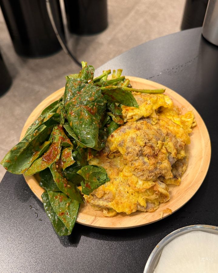 노릇하게 구워진 육전과 시금치 겉절이가 나무 접시에 담겨 나온 모습