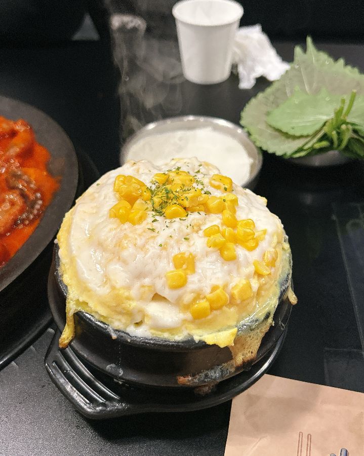 계란찜과 깻잎, 쭈꾸미 등 다양한 곁들임 메뉴들이 테이블 위에 놓여있는 모습