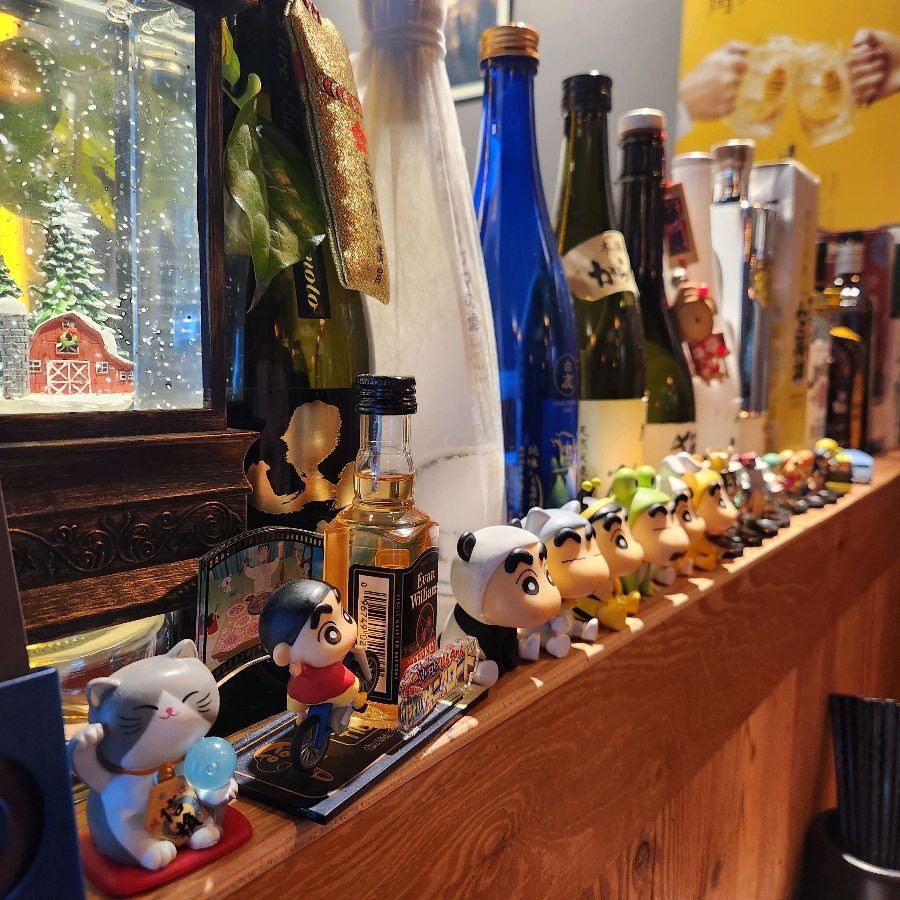 다양한 사케 병과 앙증맞은 캐릭터 피규어들이 진열된 모습