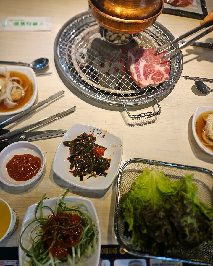 돼지갈비와 함께 다양한 곁들임 찬들이 테이블을 가득 채운 모습