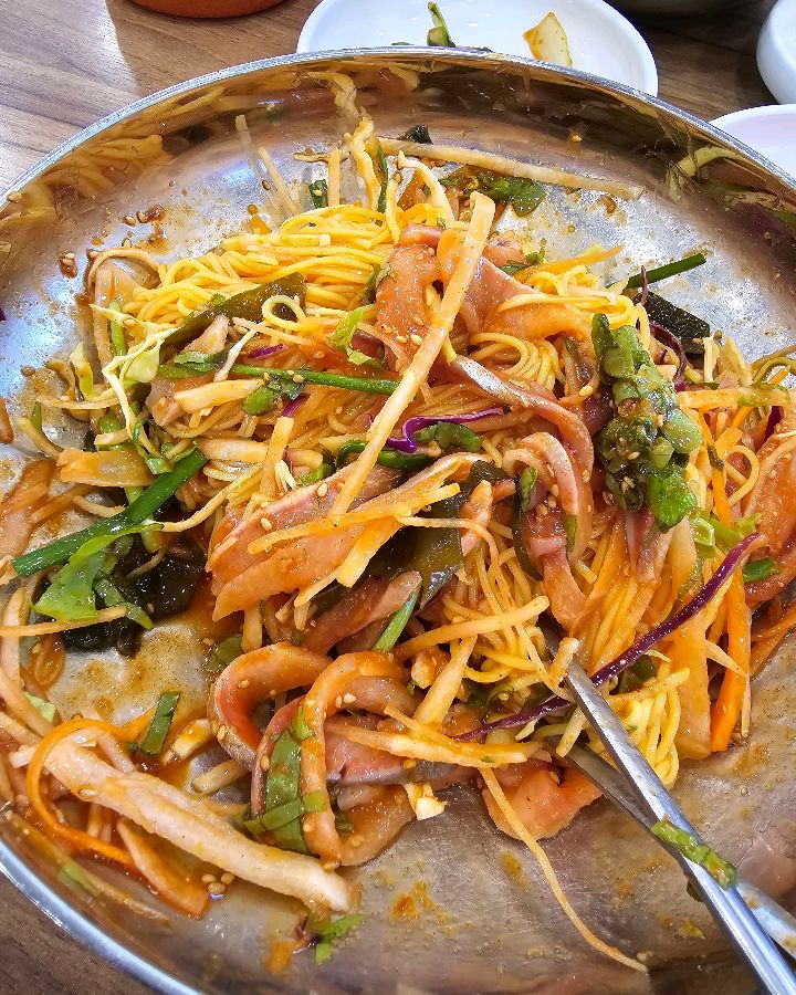 젓가락으로 회국수를 비비는 모습: 매콤달콤한 양념이 입맛을 자극한다.