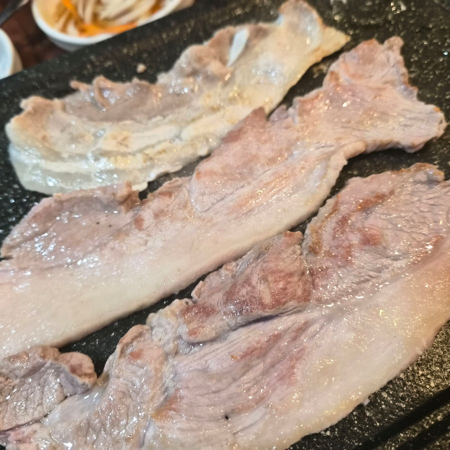 불판 위에 가지런히 놓인 삼겹살.