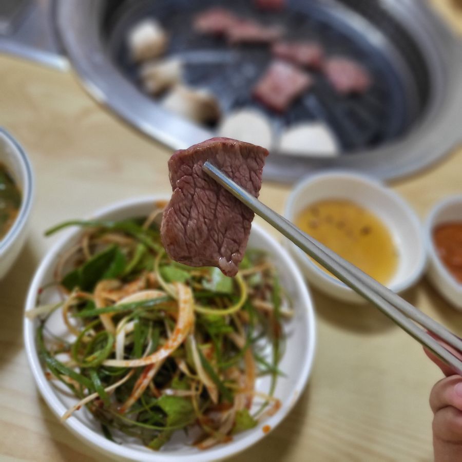 잘 구워진 칡소 한 점을 젓가락으로 들어 올린 모습, 윤기가 자르르 흐른다.