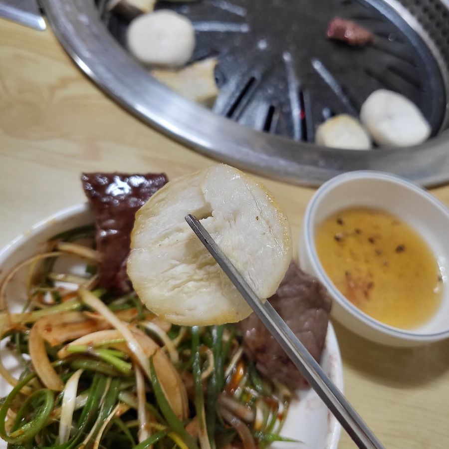 잘 구워진 버섯을 젓가락으로 집어 올린 모습, 촉촉함이 느껴진다.