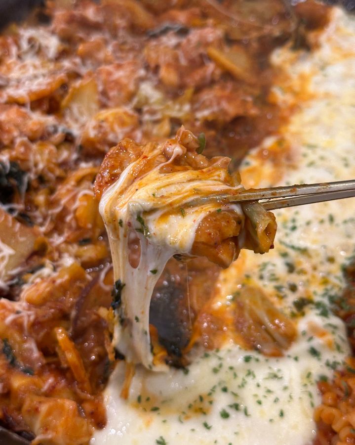 젓가락으로 들어올린 닭갈비와 녹아내리는 치즈의 환상적인 조합