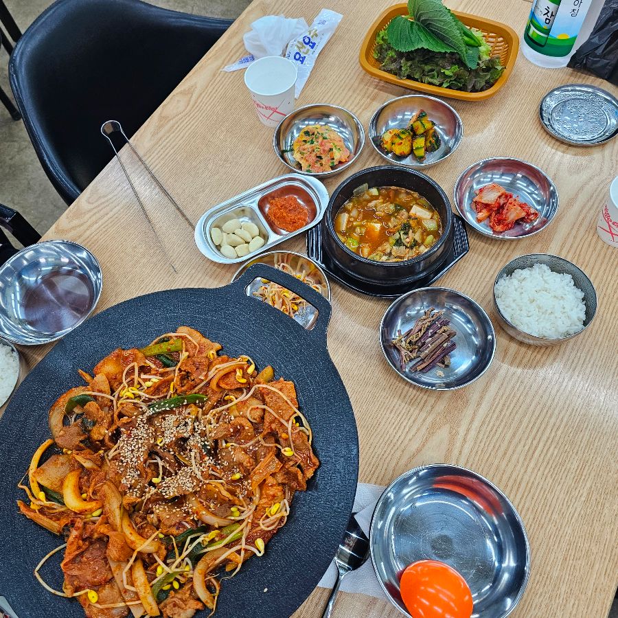 제육볶음과 다양한 밑반찬이 함께 차려진 모습. 푸짐한 양과 다채로운 색감이 식욕을 자극한다.