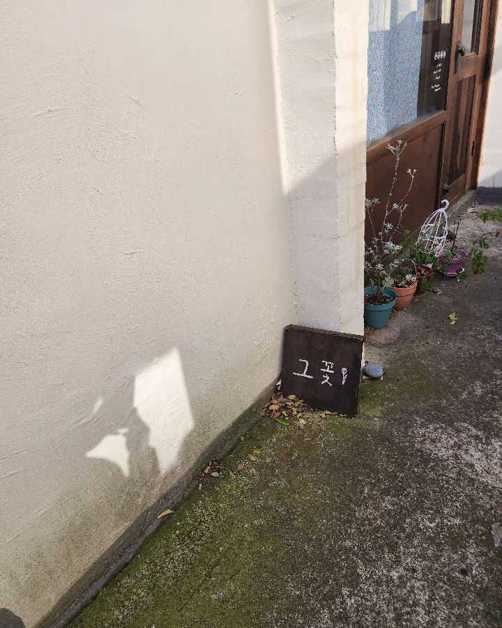 카페 입구에 놓인 작은 간판, '그 꽃'이라는 글씨가 눈에 띈다.