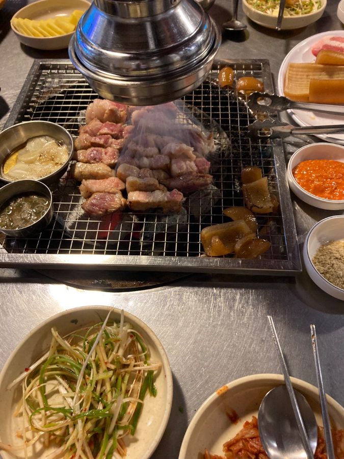 불판 위에 가지런히 놓인 고기와 곁들임 채소들