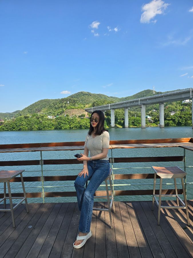 강을 바라보며 편안하게 앉아있는 여성의 모습입니다.