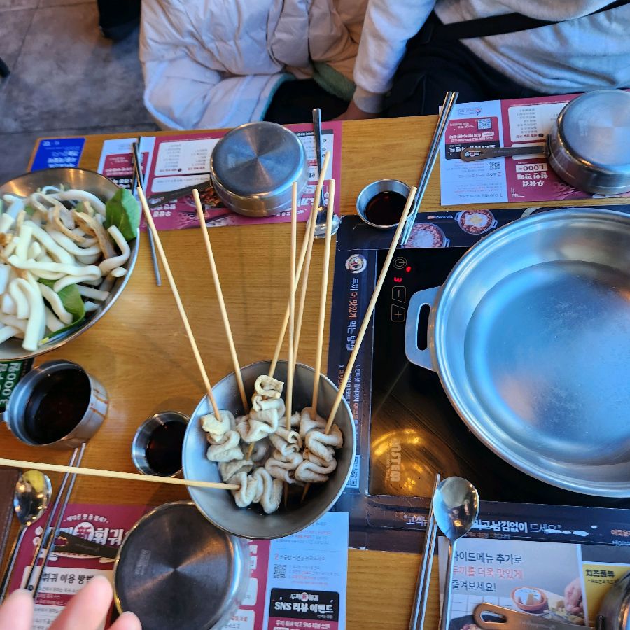 테이블 위 떡볶이 냄비와 다양한 식기류