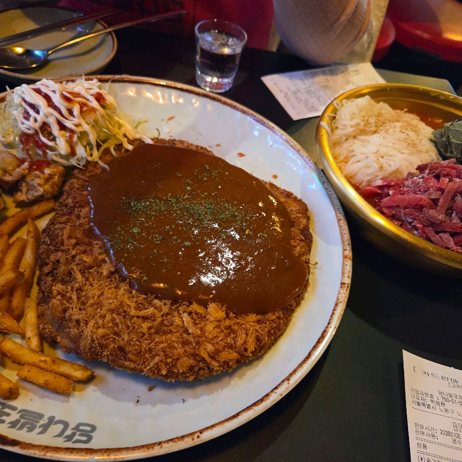 돈까스와 육회가 함께 놓인 푸짐한 한 상 차림