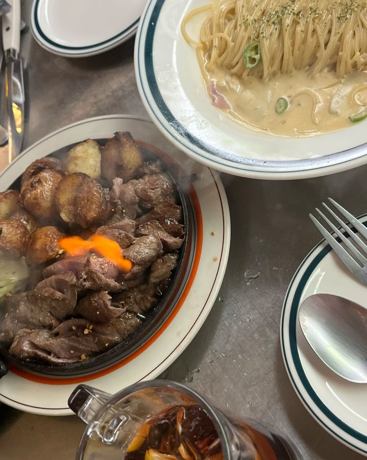 뜨거운 철판 위에서 지글거리는 스테이크와 구운 감자의 모습