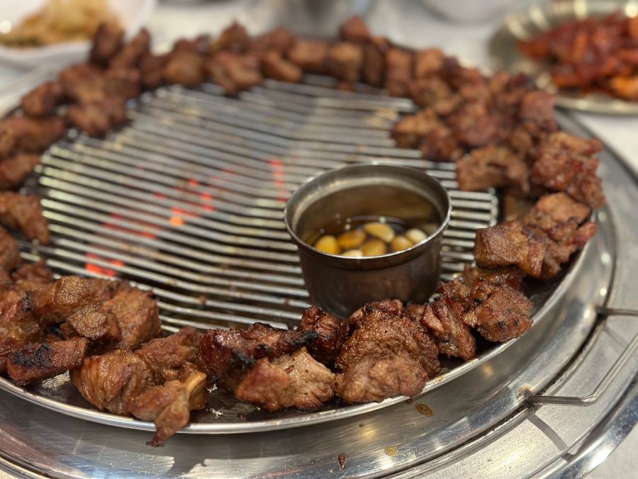 숯불 위에서 노릇하게 구워진 돼지 왕갈비의 클로즈업, 윤기가 흐르고 먹음직스러운 모습