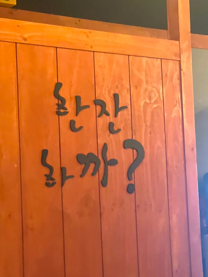따뜻한 느낌의 나무 벽에 쓰여진 '한잔하까?' 문구
