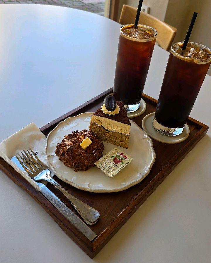 스콘과 티라미수, 아이스 아메리카노 두 잔이 나무 트레이에 담겨 제공되는 모습