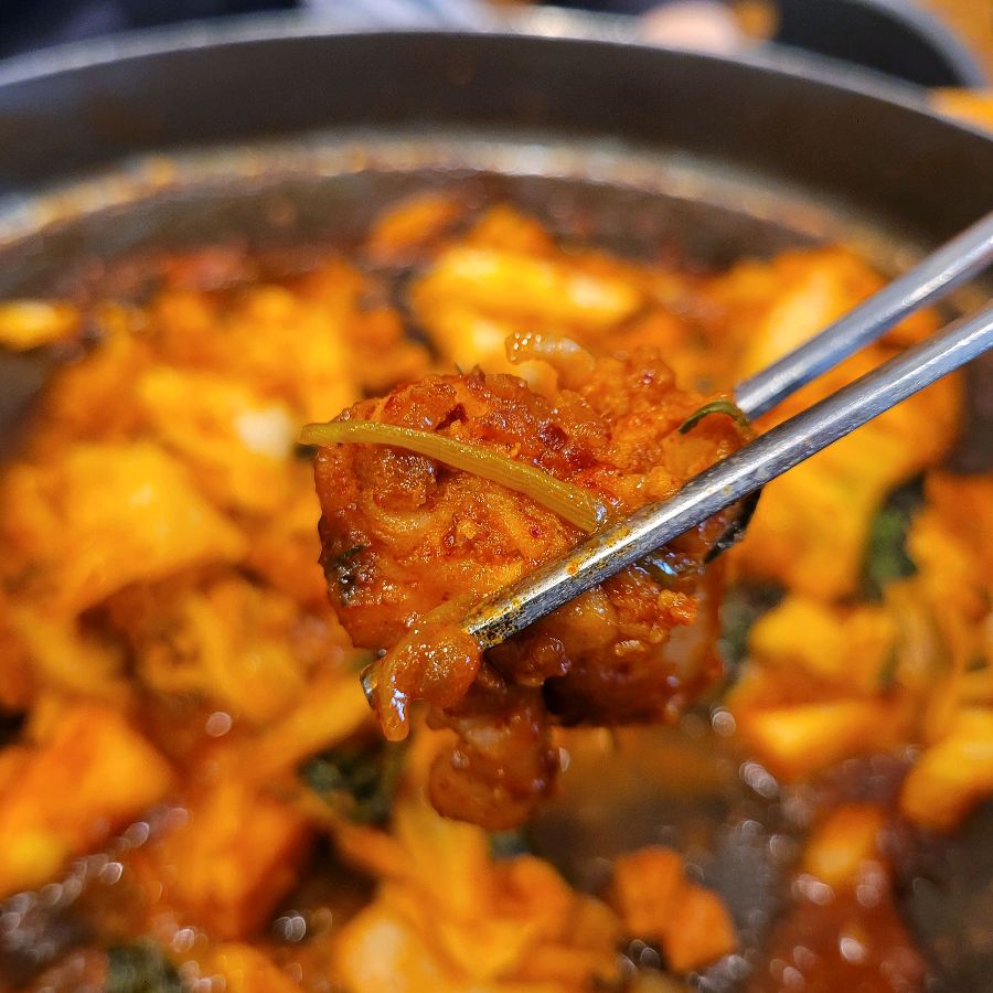 젓가락으로 닭갈비를 집어 올리는 모습