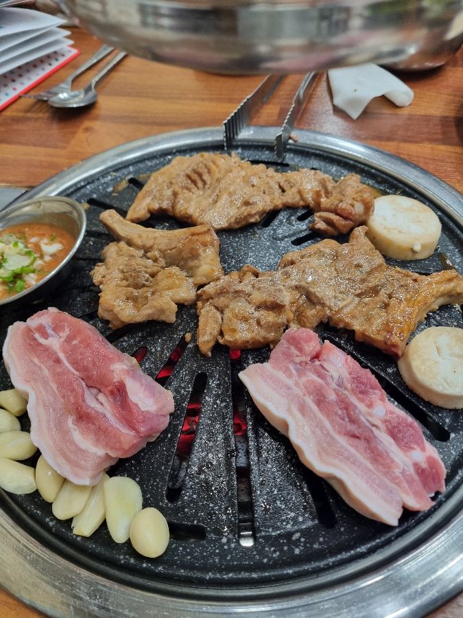 숯불 위에서 익어가는 돼지갈비와 삼겹살