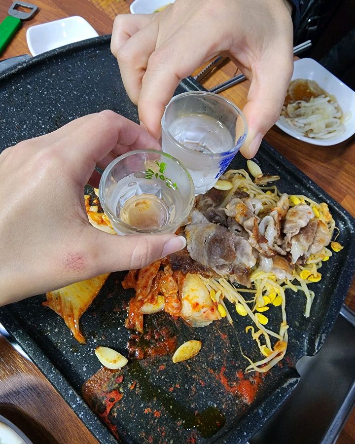 구워진 대패삼겹살에 소주잔을 기울이는 모습