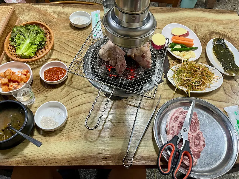 목살과 다양한 밑반찬이 차려진 테이블