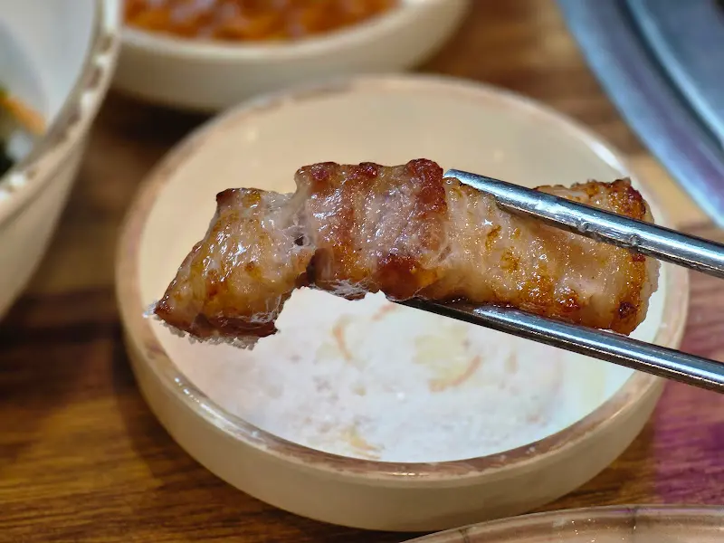 소금에 찍어 올린 삼겹살 한 점