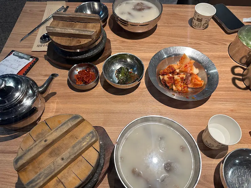 테이블 위에 놓인 설렁탕과 돌솥밥, 반찬들의 모습