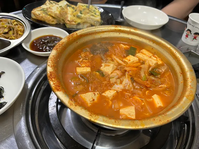 테이블 위에 놓인 김치찌개 냄비와 다양한 반찬들
