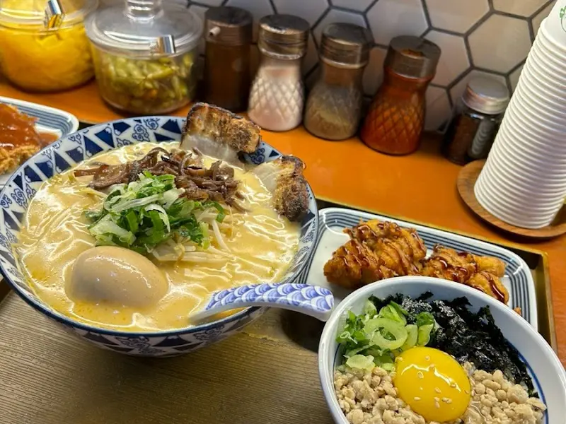 테이블 위에 놓인 숯불고기라멘과 돈카츠카레덮밥, 사이드 메뉴 사진
