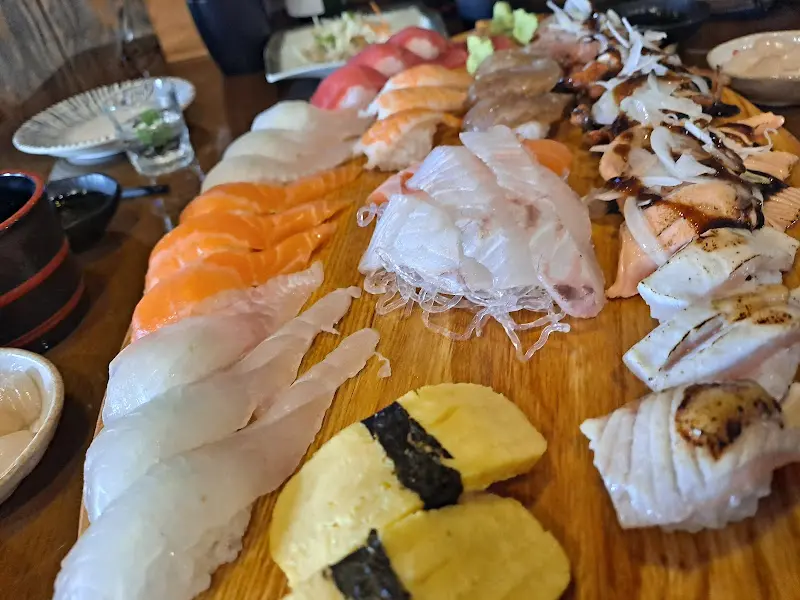 다양한 종류의 초밥들이 나무 도마 위에 푸짐하게 담겨 있는 모습