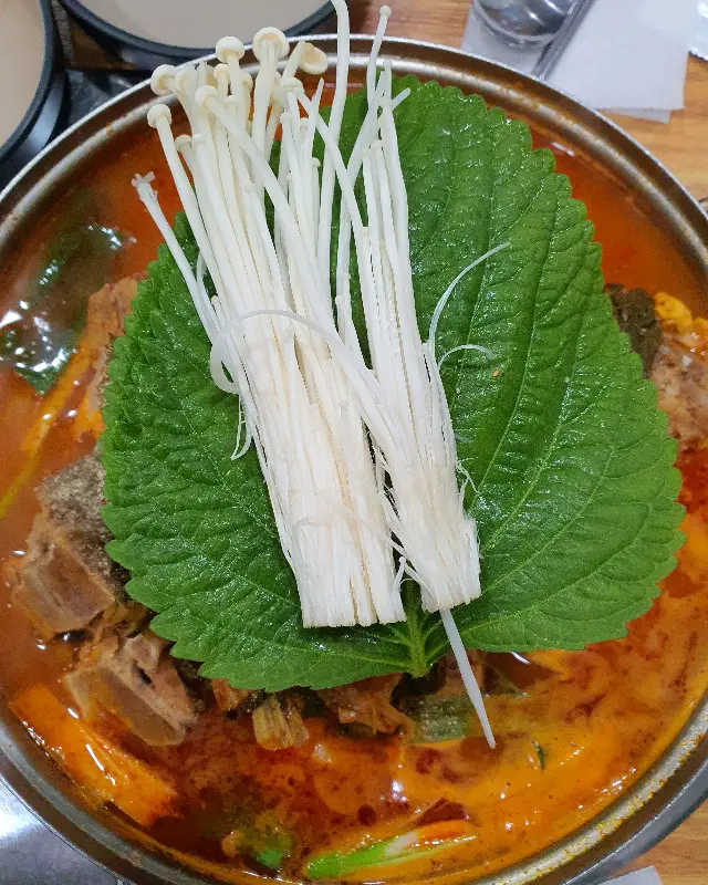 팽이버섯이 수북하게 올려진 감자탕의 모습