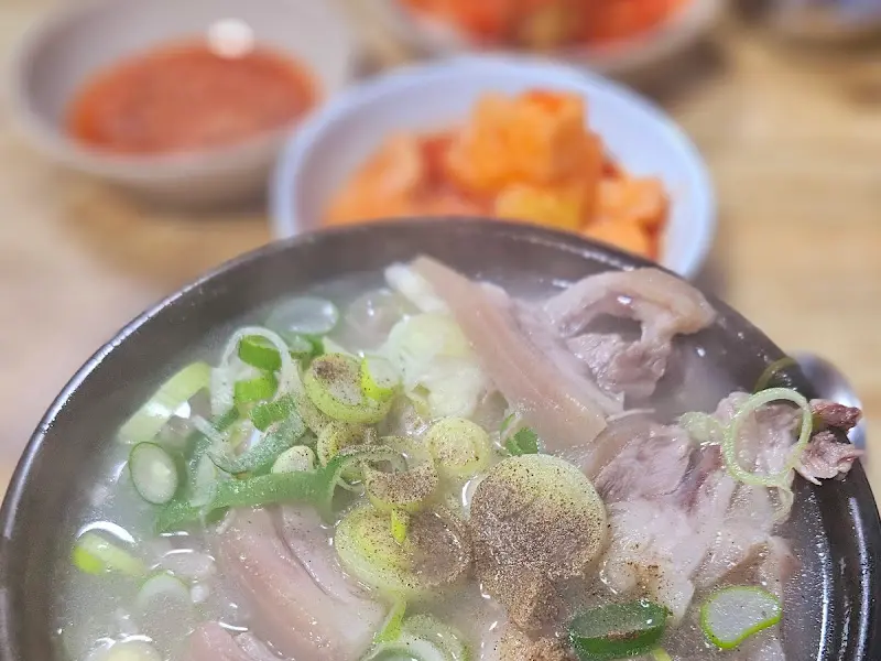 돼지국밥과 밑반찬 김치, 깍두기, 새우젓이 함께 있는 모습