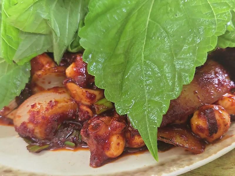 접시에 담긴 돌문어볶음 클로즈업. 깻잎이 덮여 있다.