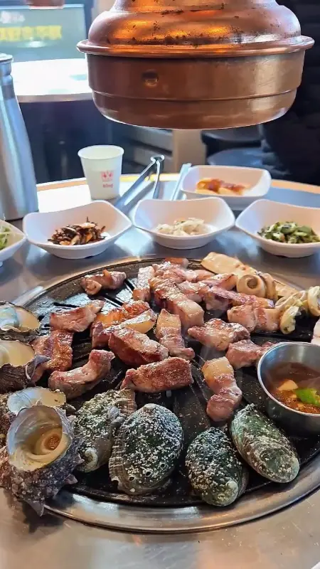 불판 위에서 맛있게 익어가는 흑돼지와 해산물