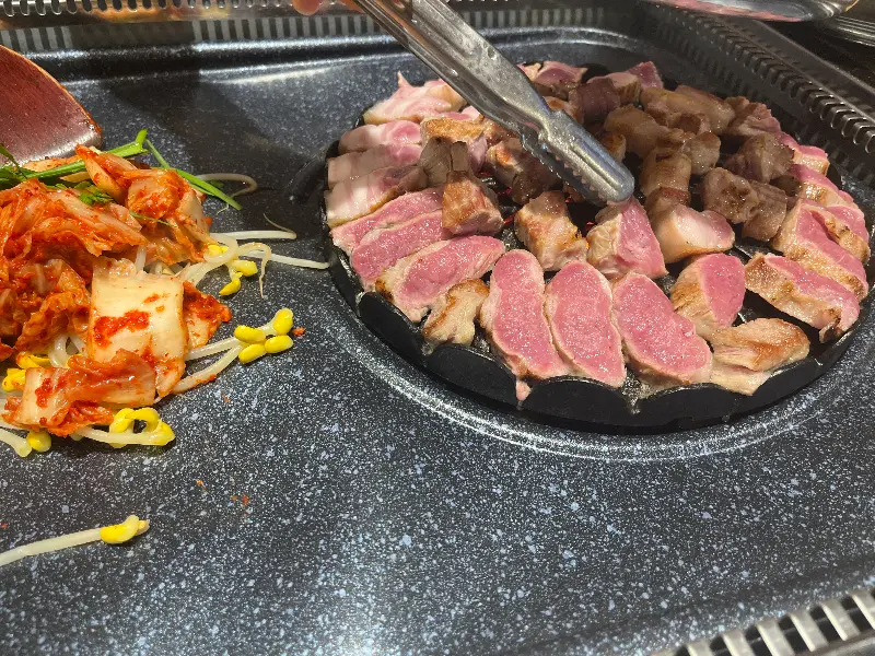 불판 위에서 맛있게 익어가는 김치와 콩나물, 그리고 고기