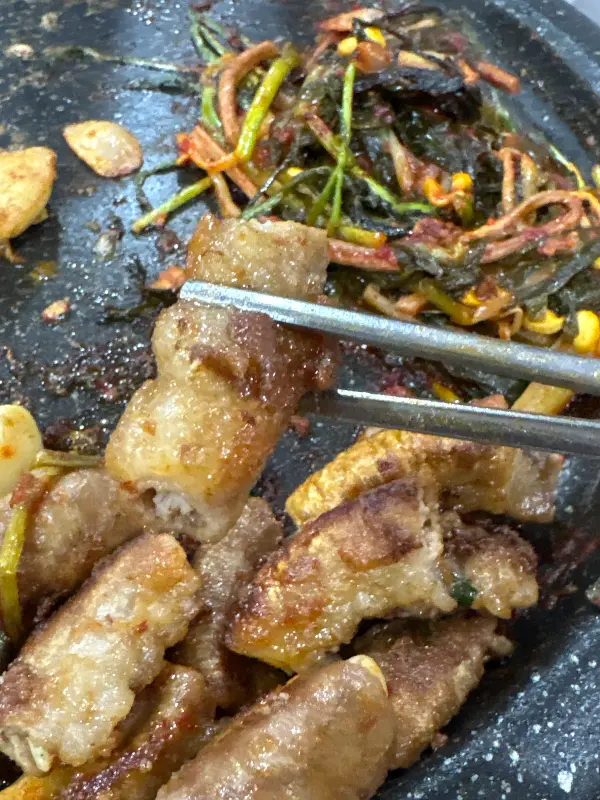 젓가락으로 곱창을 들어 올리는 모습, 곱이 꽉 차 있는 것이 보인다.