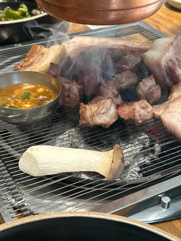 두툼하게 썰린 흑돼지 근고기가 숯불 위에서 익어가는 모습
