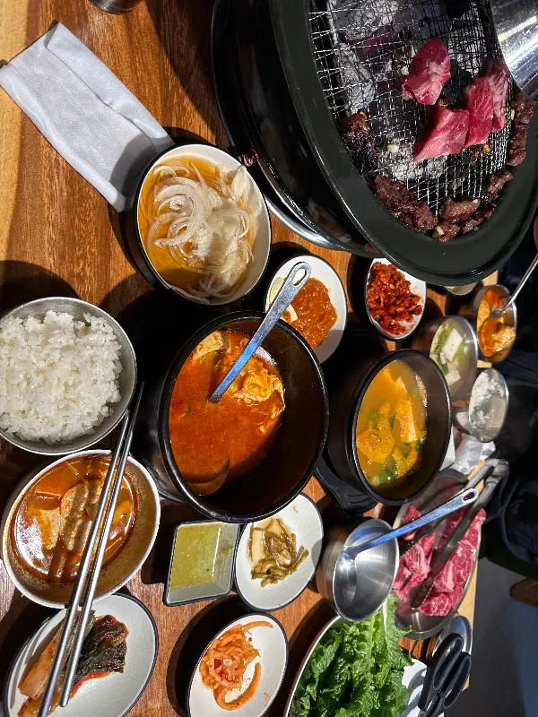 테이블 가득 차려진 곁들임 반찬과 화로구이