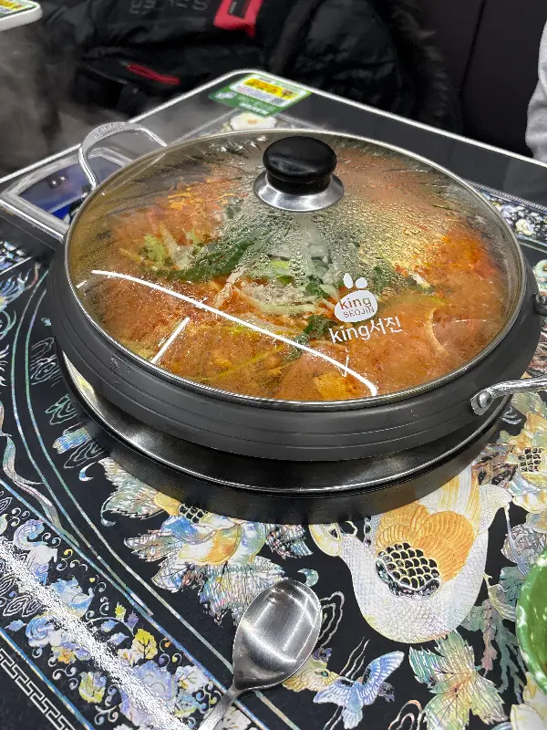 뚜껑이 덮인 채로 테이블에 놓인 부대찌개 냄비