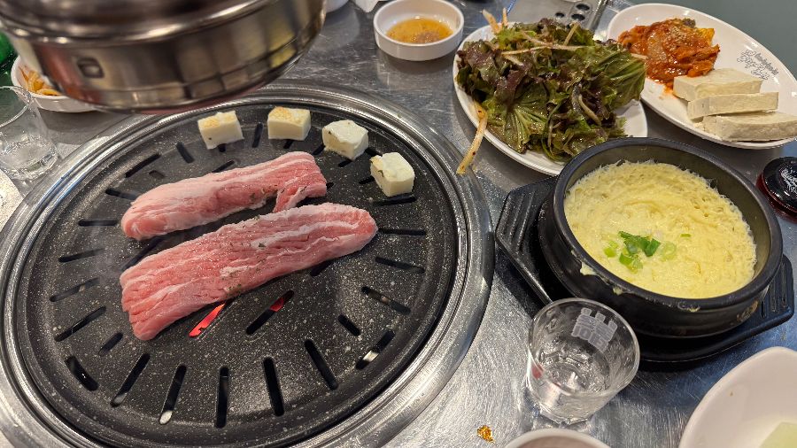 불판 위의 삼겹살과 밑반찬