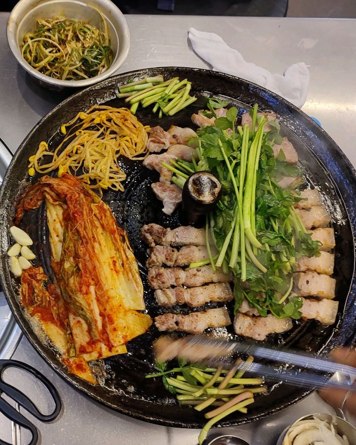 솥뚜껑에 구워지는 삼겹살과 김치