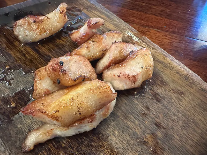 잘 구워진 고기가 나무 도마 위에 먹기 좋게 잘려 올려져 있다.