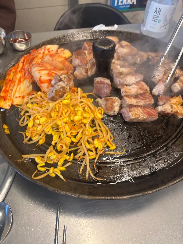 솥뚜껑에 구워지는 삼겹살과 김치, 콩나물