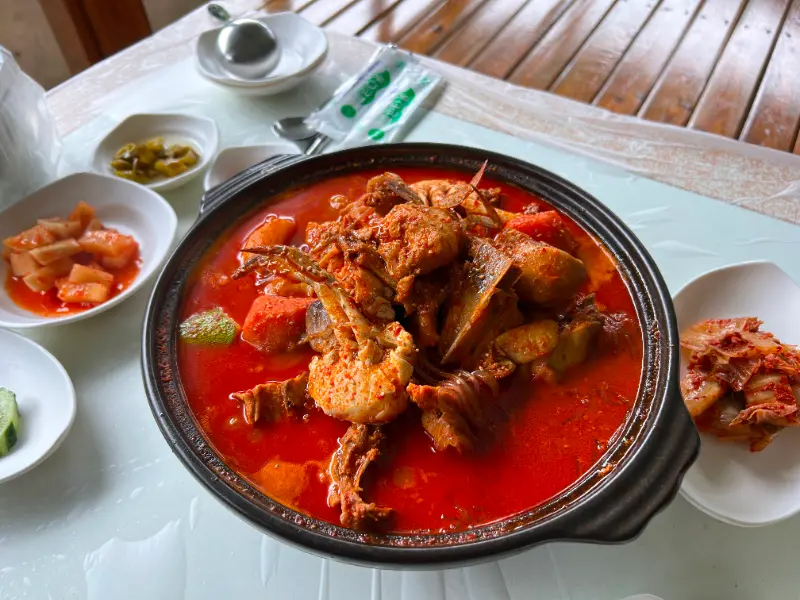 테이블 위에 놓인 꽃게 닭볶음탕과 밑반찬들