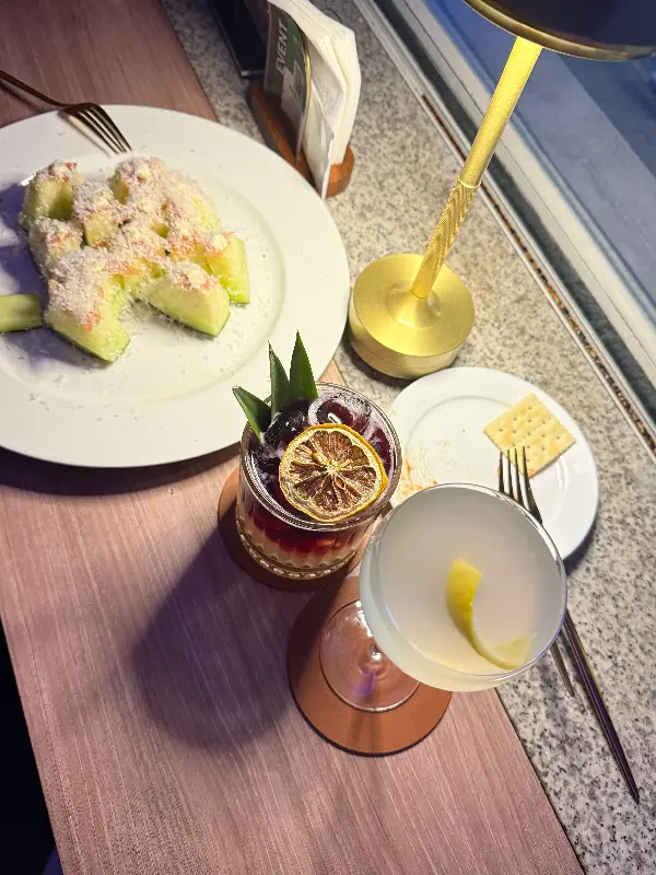 테이블 위에 놓인 두 잔의 칵테일과 과일 안주