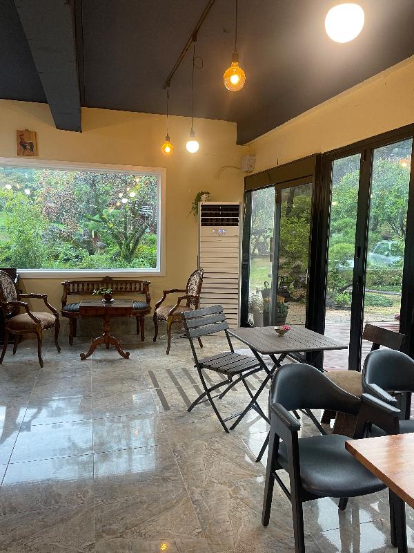 통창 너머로 정원이 보이는 아늑한 카페 내부