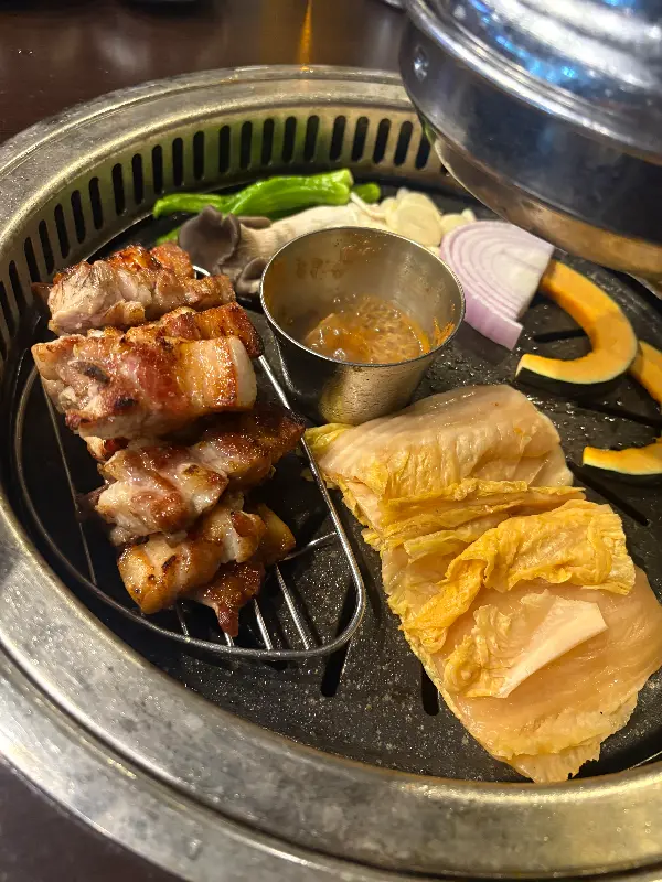 숯불 위에서 구워지는 돼지고기와 채소