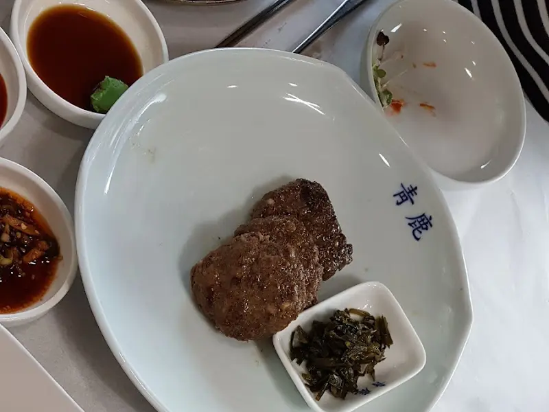 접시 위에 뭉티기와 나물이 담겨 있다.