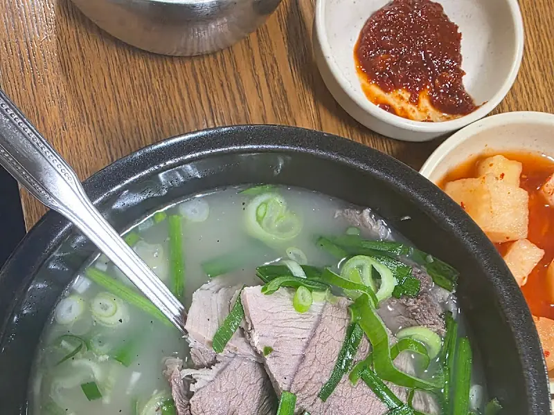 뚝배기 가득 담긴 국밥과 맛깔스러운 반찬들