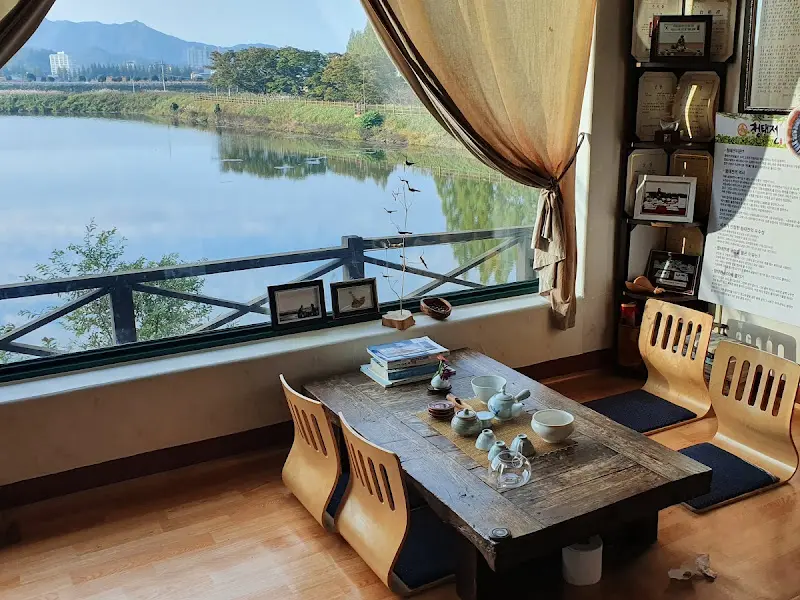 창밖의 아름다운 저수지 풍경을 바라보며 차를 즐기는 모습