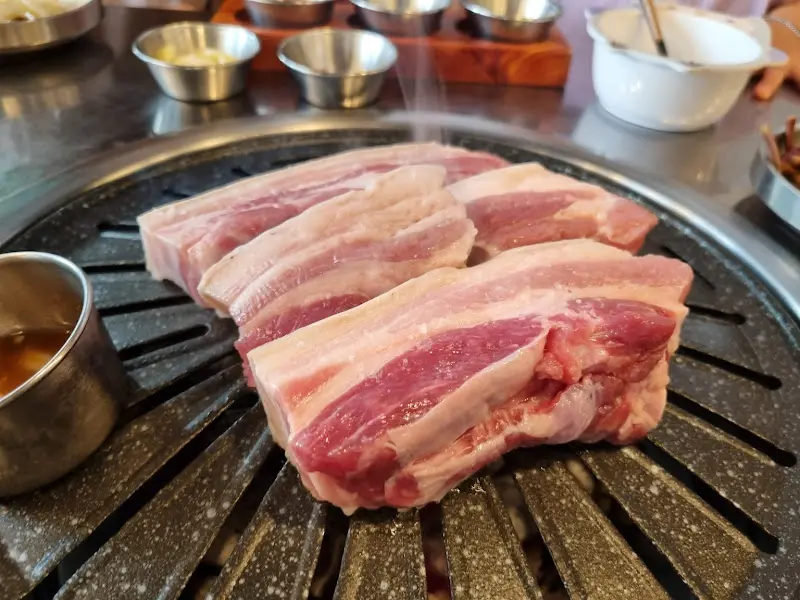 두툼한 흑돼지 오겹살이 숯불 위에서 맛있게 익어가는 모습